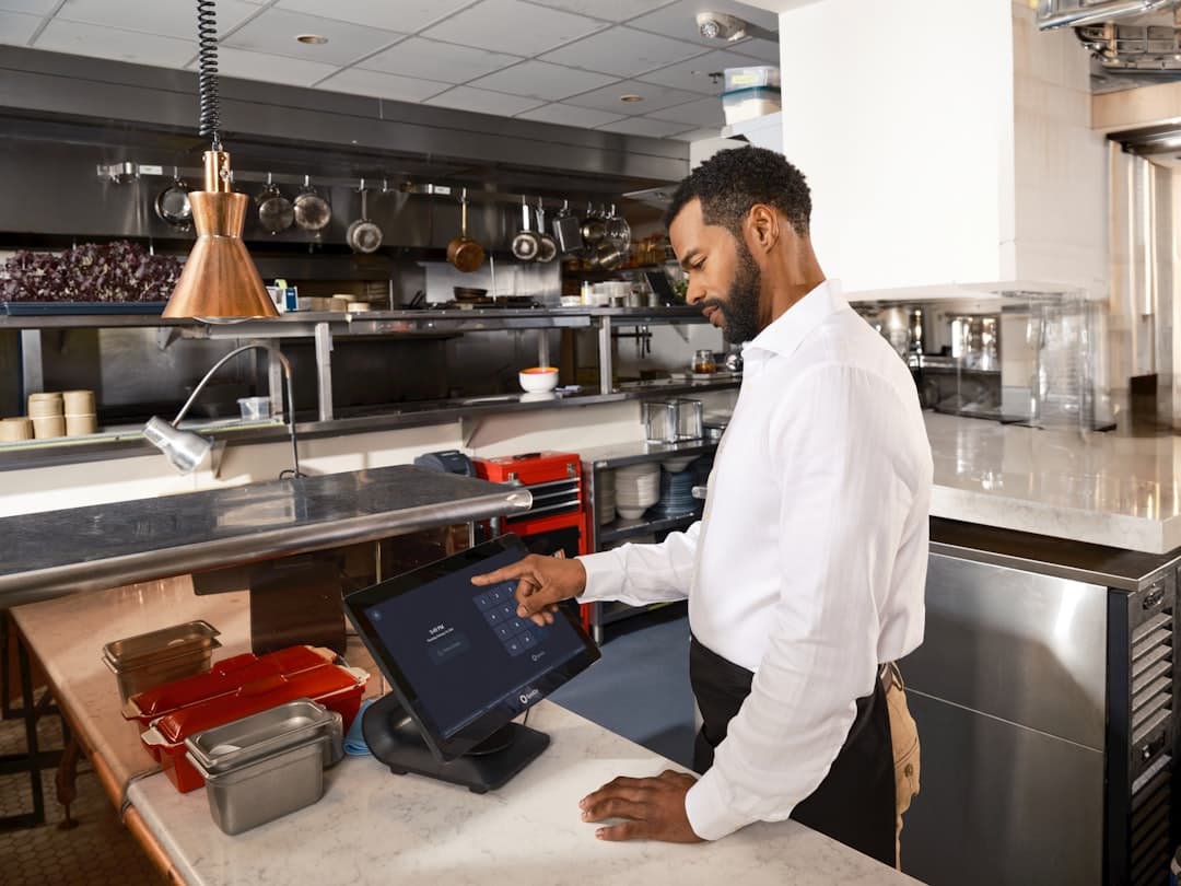 Restaurant manager configuring online ordering checkout on laptop and smartphone
