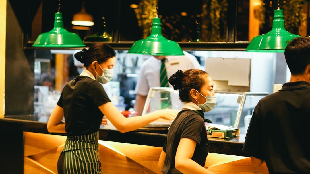 Organized restaurant pickup counter with clear signage and a staff member handing a takeout order to a customer